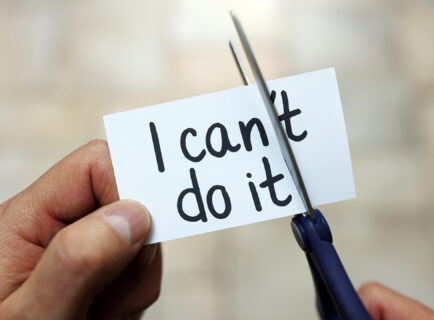 Man using scissors to remove the word can't to read I can do it concept for self belief, positive attitude and  motivation