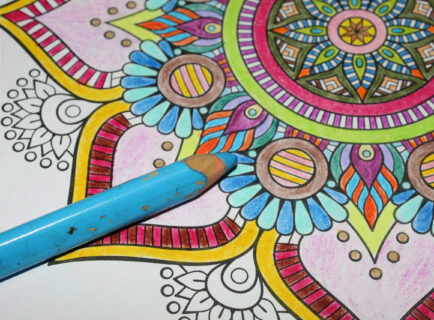 Colored pencil lying on a colored mandala drawing Mandala